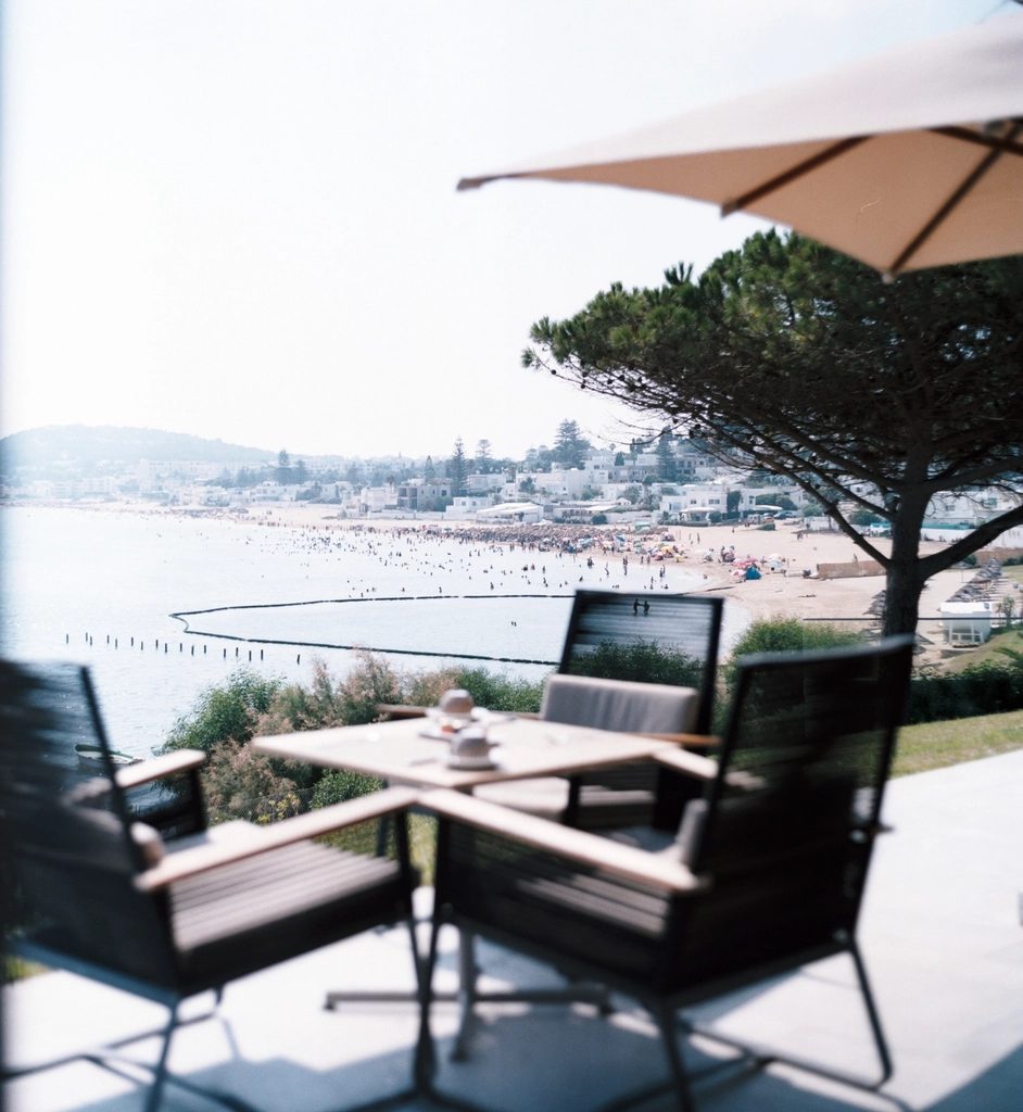 A private terrace with two lounge chairs and a parasol, looking out over a bay from a hillside.