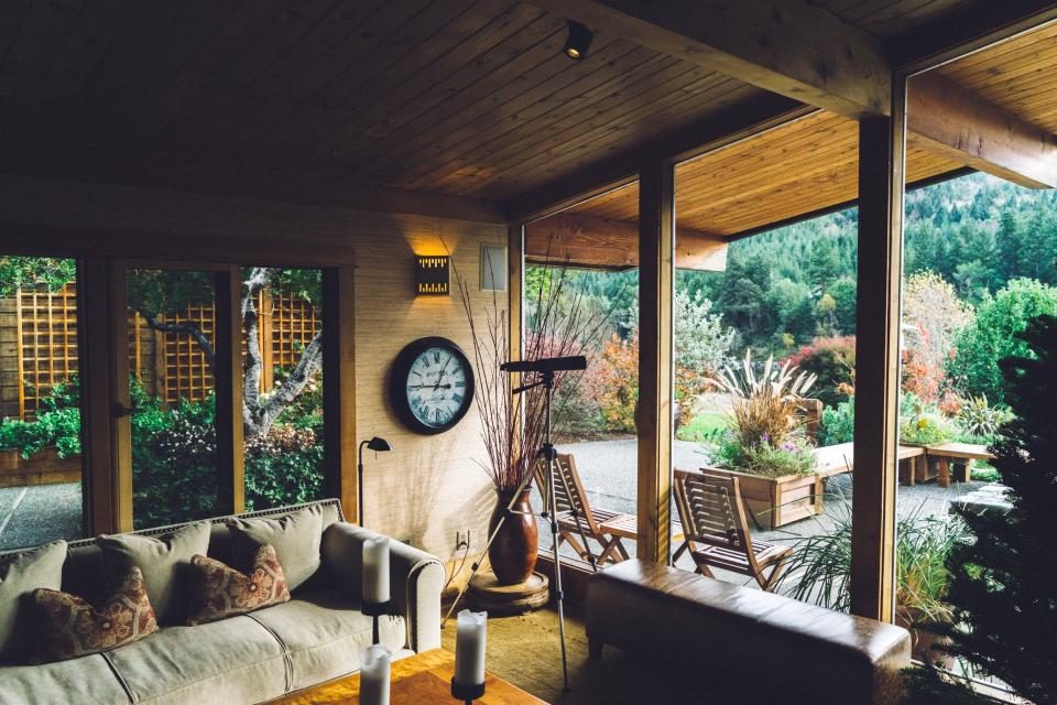 A mid-century lounge with timber ceilings, low seating and a full wall of glass onto a garden.