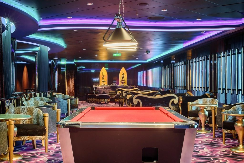 A dim, high-ceilinged games lounge with pool tables, banquette seating and warm overhead lighting.